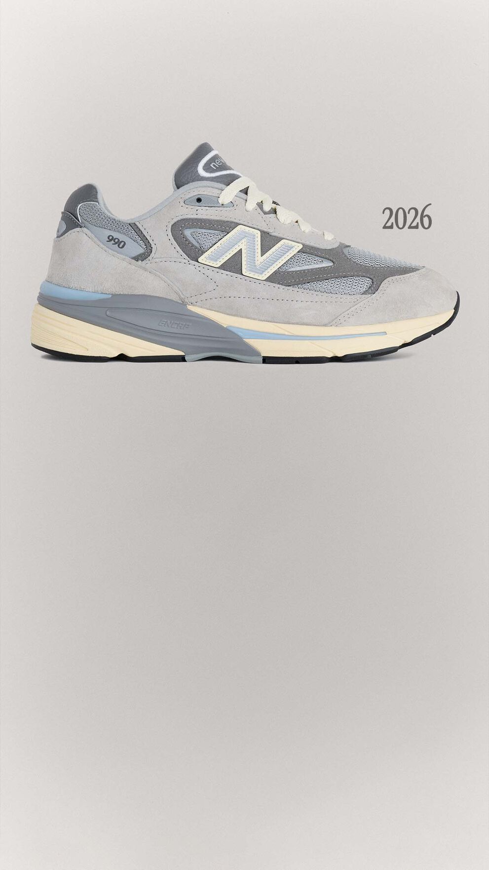 A grey 990v7 sneaker sitting on a grey background.