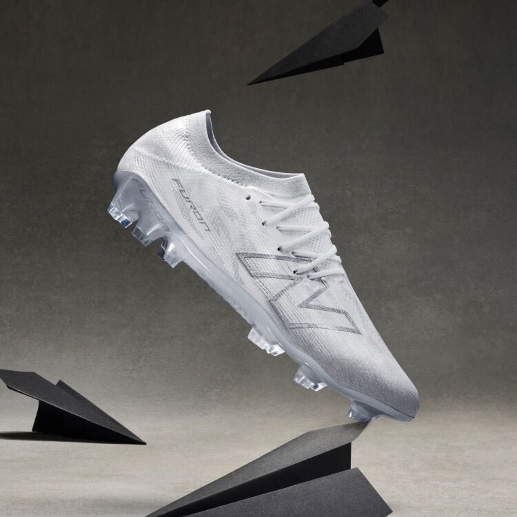 A bright yellow soccer cleat with black and red accents is displayed on its side among several glass prisms on a neutral gray surface.