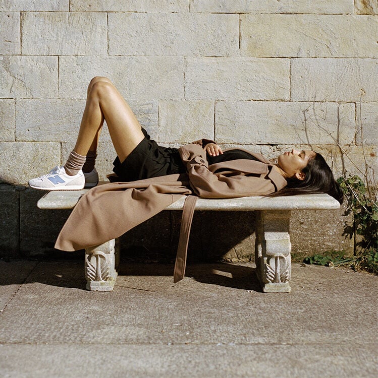 A woman wearing the 471 lies on a stone bench 