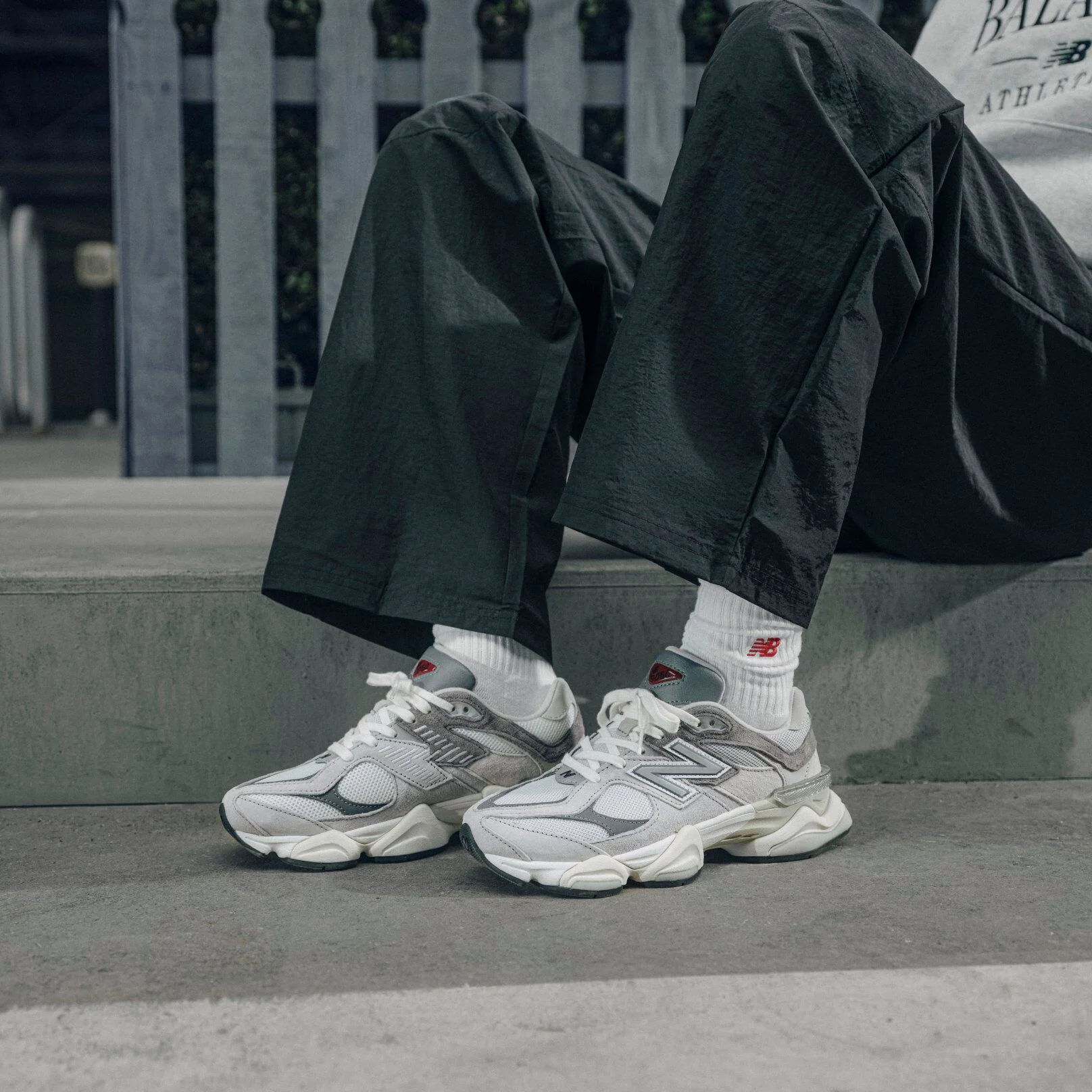 A person sitting wearing grey New Balance 9060's