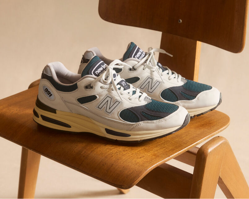 A pair of New Balance Made in UK sneakers in front of a rabbit in a brown textured studio environment. 