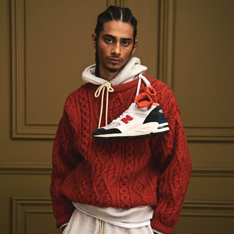 A man wearing a MADE in USA hoodie layered under a red sweater.