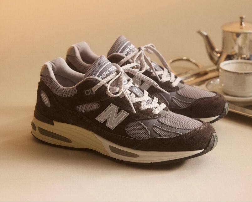 A pair of New Balance Made in UK sneakers in front of a rabbit in a brown textured studio environment. 