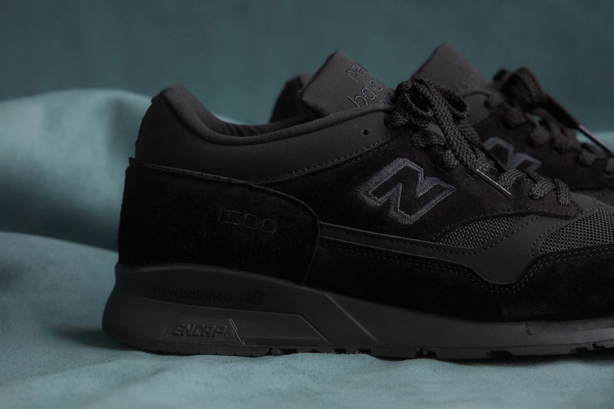 A close up view of the heel of a New Balance Made in UK sneaker on a flowing blue sheet backdrop.  