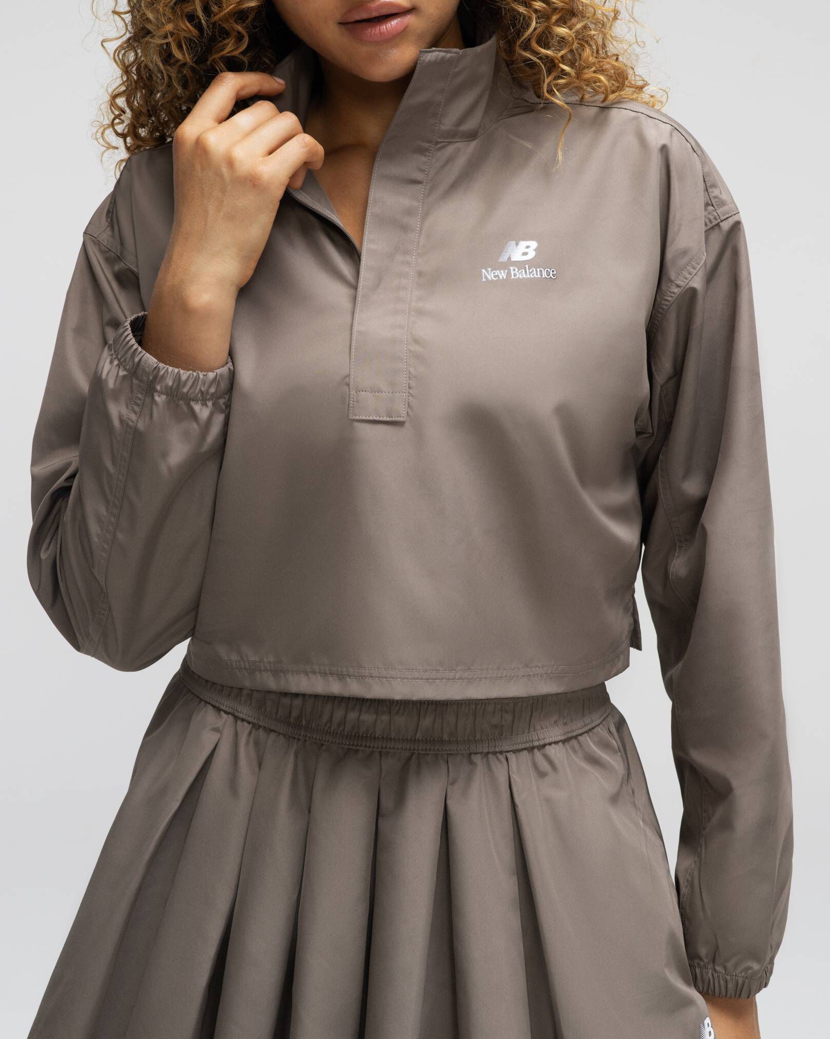 A woman wearing New Balance standing against a grey studio backdrop 